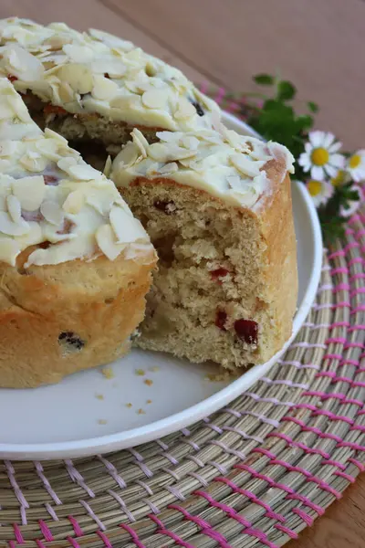 Paskalya için badem ve beyaz çikolata jölesiyle dilimlenmiş tatlı ekmek. Tahta masadaki beyaz tepside kır çiçekleriyle birlikte.