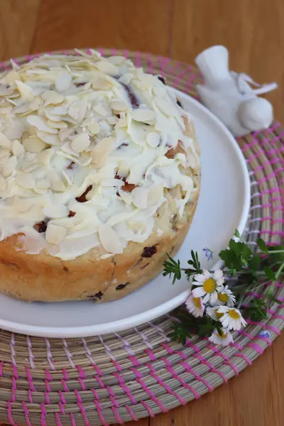 Paskalya için badem ve beyaz çikolata jöleli yuvarlak tatlı ekmek. Tahta masadaki beyaz tepside kır çiçekleriyle birlikte.