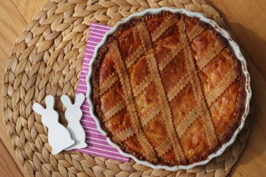 Pastiera adındaki geleneksel İtalyan paskalya pastası seramik tavşanlarla ahşap masada.