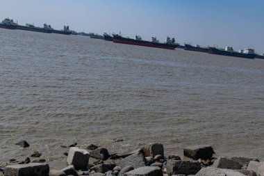 Parlak bir okyanus gökyüzü, Patenga kıyısında görünen bir gemi, sakin deniz manzarasını yakalıyor. Bangladeş 'te seyahat, sahil manzaraları, deniz taşımacılığı ve huzurlu okyanus manzaraları için ideal..