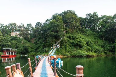 Rangamati Gölü 'nün manzaralı yamacında sakin sular ve yemyeşil sularla çevrili tekneler huzur içinde dinleniyor. Bu huzurlu ortam Bangladeş 'in kırsal cazibesini ve doğal huzurunu güzel bir şekilde yansıtıyor..