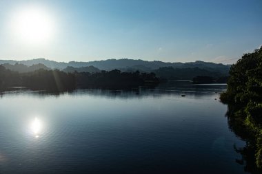 Yeşil tepelerin ve Kaptai Gölü 'nün sakin sularının sakin manzarası, altın ışığı, barışçıl yansımaları ve seyahat, manzara ve doğa fotoğrafçılığı için doğal uyum.