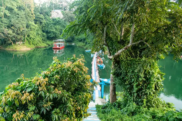 Kaptai Gölü 'nün sakin sularına yavaşça inen yeşil tepe yamaçlarının büyüleyici görüntüsü doğal uyumu, bereketli manzaraları ve seyahat, doğa ve manzara fotoğrafçılığı için mükemmel sükuneti sergiliyor..