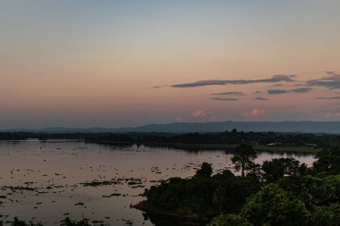 Gün batımı Kaptai Gölü ve dağ sırtı üzerinde altın bir parıltı bırakır ve nefes kesici bir manzara yaratır. Sakin sular rengarenk gökyüzünü yansıtır, bu sakin manzaranın dingin güzelliğini yakalar..
