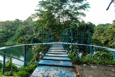 Rangamati tepelerinin sakin bir gölün üzerinde gökyüzü ile buluşmasının çarpıcı görüntüsü, dingin yansımaları ve canlı yeşillikleri yakalıyor. Doğa, seyahat, manzara ve barışçıl doğa fotoğrafçılığı temaları için idealdir..