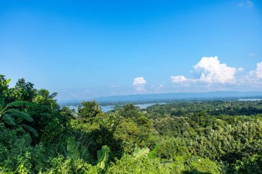 Rangamati, Bangladeş 'te, parlak bir gökyüzünün altında yuvarlanan tepeler, canlı doğal güzellik gösterisi. Bu huzurlu manzara yemyeşil ve açık gökyüzünü yakalar, doğa ve seyahat fotoğrafçıları için mükemmeldir..