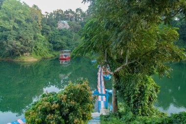 Rangamati, Bangladeş 'teki sık yeşil yapraklar ve orman tepeleriyle çevrili sakin bir nehir kıvrımına demirlemiş sakin bir yüzen ev. Seyahat fotoğrafçılığı, doğa severler ve eko-turizm keşifleri için mükemmel sakin bir sahne..