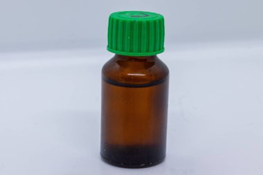 Yeşil kapaklı kehribar cam şişe. Yağ, ilaç ya da sıvı depolamak için ideal. Beyaz arka planda izole edilmiş, ilaç, kozmetik ve aromaterapi ürün sunumları için mükemmel..