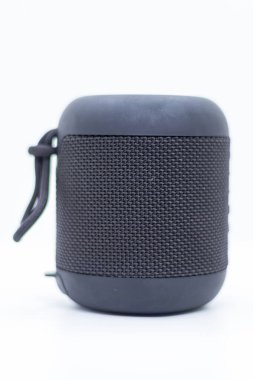 Beyaz stüdyo arka planında izole edilmiş, kumaş örgü kapaklı siyah taşınabilir bluetooth hoparlörünün yüksek çözünürlüklü görüntüsü. Ses teknolojisi, kablosuz ses sistemleri, müzik aksesuarları ve yaşam tarzı içeriği için mükemmel..