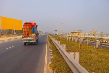 A busy Dhaka Mawa Highway filled with multiple vehicles including cars, trucks, and buses during daytime. Shows heavy traffic flow on a major highway in Bangladesh, capturing urban transport dynamics.