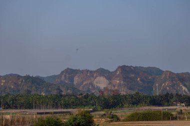 Bereketli bir palmiye ağacının üzerindeki görkemli kayalık tepe kuleleri nefes kesen ve ahenkli bir manzarada canlı tropik yeşillikle harmanlanmış engebeli doğal güzellikleri harmanlıyor..