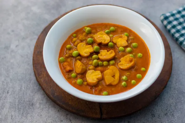 Spicy button mushroom curry cooked with green peas.