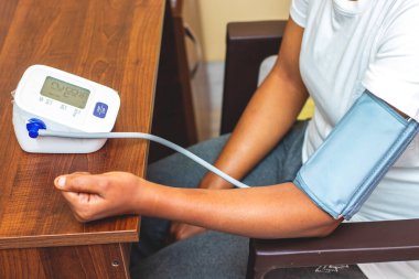 Dijital bir Sphygmomanometre üzerinde kan basıncını ölçen bir kadının seçici odağı.