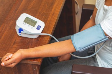 selective focus of a lady measuring blood pressure on a digital Sphygmomanometer. clipart
