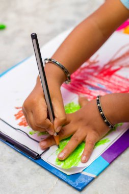 Sınıfta bir erkek bebek resim çiziyor..