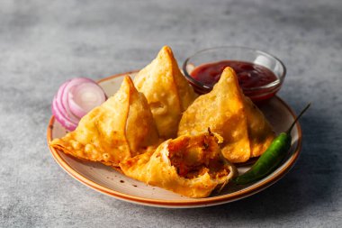 Seçici odaklı Samosa, baharatlı patates dolu hamur işi, çıtır çıtır, tuzlu, domates ve nane aromalı popüler Hint atıştırmalığı.. 