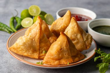 Seçici odaklı Samosa, baharatlı patates dolu hamur işi, çıtır çıtır, tuzlu, domates ve nane aromalı popüler Hint atıştırmalığı.. 