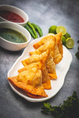 selective focus Samosa, Spiced potato-filled pastry, crispy, Savory, popular Indian snack with tomato and mint chutney.  clipart