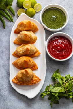 Seçici odaklı Samosa, baharatlı patates dolu hamur işi, çıtır çıtır, tuzlu, domates ve nane aromalı popüler Hint atıştırmalığı.. 