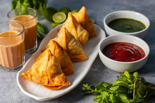 Seçici odaklı Samosa, baharatlı patates dolu hamur işi, çıtır çıtır, tuzlu, domates ve nane aromalı popüler Hint atıştırmalığı.. 