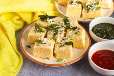 Ünlü Gujrati atıştırmalığı Dhokla nane ve domates sosuyla süslenmiş un ve şeker şurubuyla yapıldı.. 