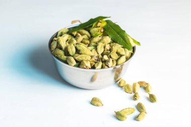 Kakule veya Elaichi Hint aromatik baharatının tatlı ve tuzlu yemeklerde kullanıldığı seçici odak noktası. Beyaz bir arkaplanda. 