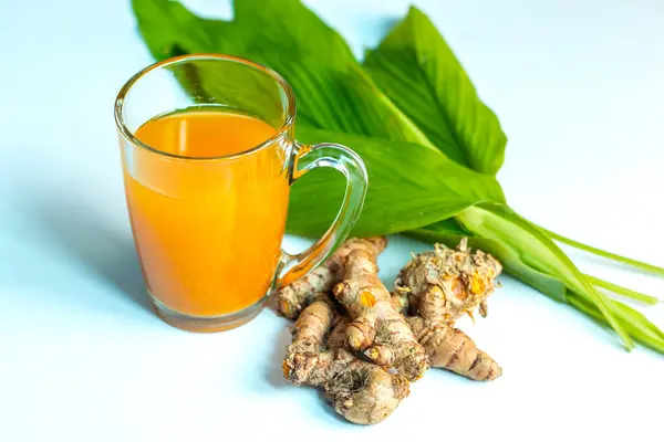 stock image Raw Turmeric Juice in a glass with wooden background for body detox and healthy liver.