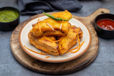 Siyah seramik tabakta yeşil pudina sosu ve domates sosuyla servis edilen Hint atıştırmalığı 