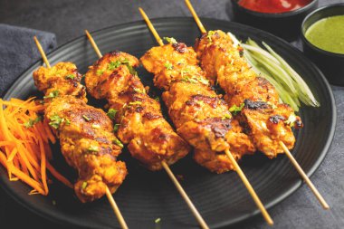 Deliciously Spiced Chicken Tikka Kabab, A Flavourful Grilled Delight with Tangy Marinade and Smoky Charcoal Aroma Serve with Mint and Tomato Chutney. Selective focus. clipart