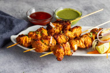 Lezzetli Baharatlı Tavuk Tikka Kebap, Tangy Marinade ile Lezzetli Izgara Lezzet ve Nane ve Domates soslu Tütsülenmiş Kömür Aroma Servisi. Seçici odak.