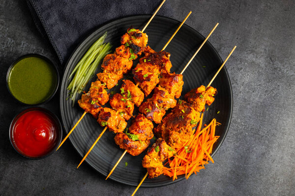 Deliciously Spiced Chicken Tikka Kabab, A Flavourful Grilled Delight with Tangy Marinade and Smoky Charcoal Aroma Serve with Mint and Tomato Chutney. Selective focus.