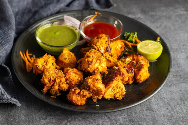 stock image Deliciously Spiced Chicken Tikka Kabab, A Flavourful Grilled Delight with Tangy Marinade and Smoky Charcoal Aroma Serve with Mint and Tomato Chutney. Selective focus.