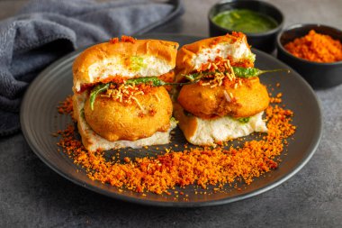 Mumbai 'nin ünlü sokak yemeklerinin seçmeli odak noktası lezzetli Vada Pav kişniş, turşu, domates sosu, kuru sarımsaklı baharat ve kızarmış kırmızı biber..