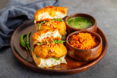 Mumbai 'nin ünlü sokak yemeklerinin seçmeli odak noktası lezzetli Vada Pav kişniş, turşu, domates sosu, kuru sarımsaklı baharat ve kızarmış kırmızı biber..