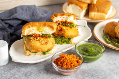 elective focus of Mumbai's famous street food delicious Vada Pav, With coriander leave chutney, tomato sauce, dry garlic chutney and fried chilli. clipart