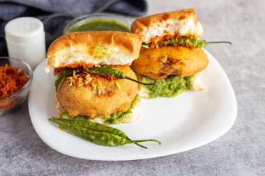 Mumbai 'nin ünlü sokak yemeklerinin seçmeli odak noktası lezzetli Vada Pav kişniş, turşu, domates sosu, kuru sarımsaklı baharat ve kızarmış kırmızı biber..