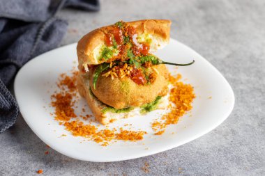 elective focus of Mumbai's famous street food delicious Vada Pav, With coriander leave chutney, tomato sauce, dry garlic chutney and fried chilli. clipart