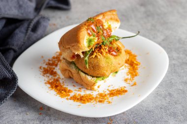 Mumbai 'nin ünlü sokak yemeklerinin seçmeli odak noktası lezzetli Vada Pav kişniş, turşu, domates sosu, kuru sarımsaklı baharat ve kızarmış kırmızı biber..