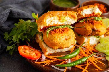 Mumbai 'nin ünlü sokak yemeklerinin seçmeli odak noktası lezzetli Vada Pav kişniş, turşu, domates sosu, kuru sarımsaklı baharat ve kızarmış kırmızı biber..