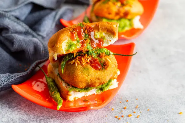 stock image elective focus of Mumbai's famous street food delicious Vada Pav, With coriander leave chutney, tomato sauce, dry garlic chutney and fried chilli.