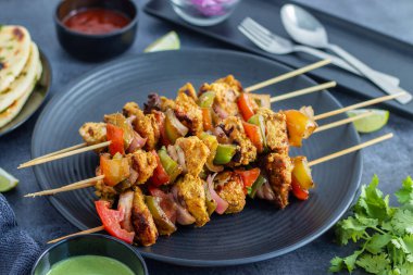 Tavuk tikka kebabı, terbiye edilmiş, baharatlı ızgara tavuk parçaları, sıklıkla nane sosu ve naan eşliğinde şiş servis edilir. Seçici odak.