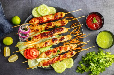 Lezzetli ızgara tavuk kebabı. Lezzetli bir yemek için taze nane sosu ve keskin domates sosuyla servis ediliyor..