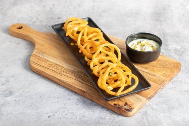 Altın sarısı, sarmal şekilli jalebiler sıcak servis edilir, kremalı, kakule kaplı hahamlarla eşleştirilir, lezzetli, aromatik ve hoşgörülü bir tatlı deneyimi yaratır..