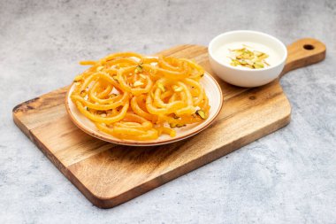 Altın sarısı, sarmal şekilli jalebiler sıcak servis edilir, kremalı, kakule kaplı hahamlarla eşleştirilir, lezzetli, aromatik ve hoşgörülü bir tatlı deneyimi yaratır..