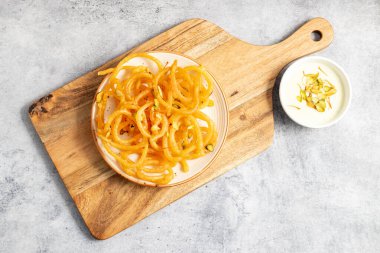 Altın sarısı, sarmal şekilli jalebiler sıcak servis edilir, kremalı, kakule kaplı hahamlarla eşleştirilir, lezzetli, aromatik ve hoşgörülü bir tatlı deneyimi yaratır..