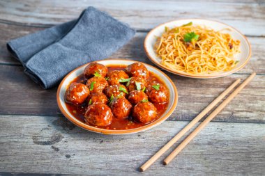 Lezzetli bir Hint-Çin yemeği için baharatlı, keskin soslu, aromalı kızarmış erişteyle servis edilen mançurya köfteleri..