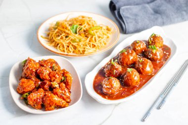 Baharatlı, keskin soslu çıtır mançurya topları, Hint-Çin ziyafeti için kızarmış erişte ve çıtır çıtır Gobi Mançuryası ile servis ediliyor..