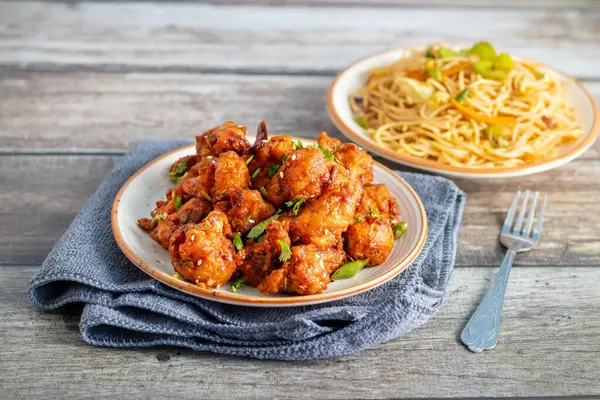 Baharatlı, keskin soslu çıtır Gobi Mançurya peyniri yanında sebzeli, sarımsaklı ve soya aromalı erişte. Lezzetli bir Hint-Çin lezzeti.!