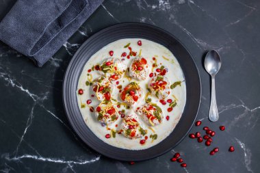 Dahi Bhalla, üzerinde keskin baharatlar, baharatlar ve nar bulunan kremalı yoğurda batırılmış, bol yağda kızartılmış mercimek köftesinden yapılan popüler bir Hint atıştırmalığı..