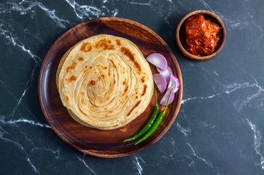 Çıtır çıtır, gevrek laccha paratha dilimlenmiş soğan, kırmızı kırmızı biber ve keskin turşu ile sıcak servis edilir. Mükemmel bir doku ve kalın tatlar karışımı yaratır..